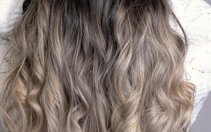 Cheveux mi-longs ondulés, dégradé de châtain vers le gris